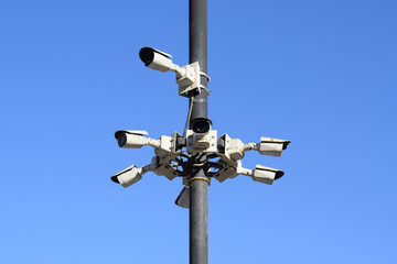 Several CCTV cameras mounted on poles with a blue sky background. Advanced security and surveillance at every corner