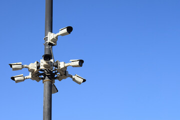 High angle view of several CCTV cameras mounted on poles with a blue sky background. Advanced security and surveillance at every corner