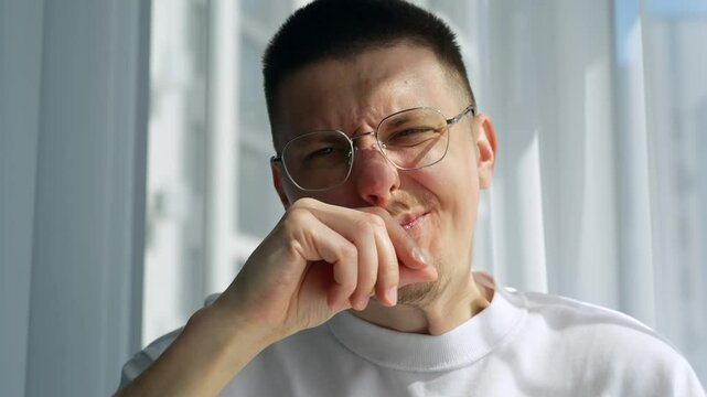 A young European guy wipes snot under his nose with his hand.
A man with a runny nose wipes his nose with his hand.
A man rubs his face with his hand in a bright room.
Cold, hand, wipe, dirty