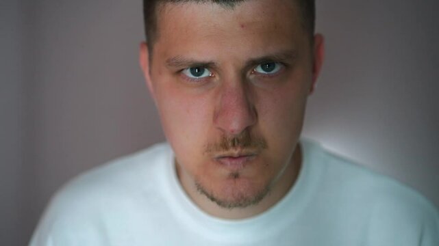 Serious and frightening facial expression of a young man in close-up.
Anger and negativity on the face.
Evil facial expression.
The young guy is very angry and clenches his mouth and cheekbones in ang