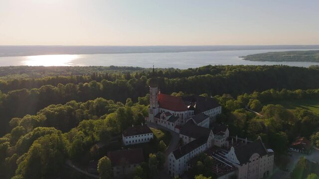 Aerial drone video of Kloster Andechs and pilgrimage church on Holy Mountain by Lake Ammersee, Bavaria, Germany. Scenic sunset view of monastery, nature, and rural landscape near Munich