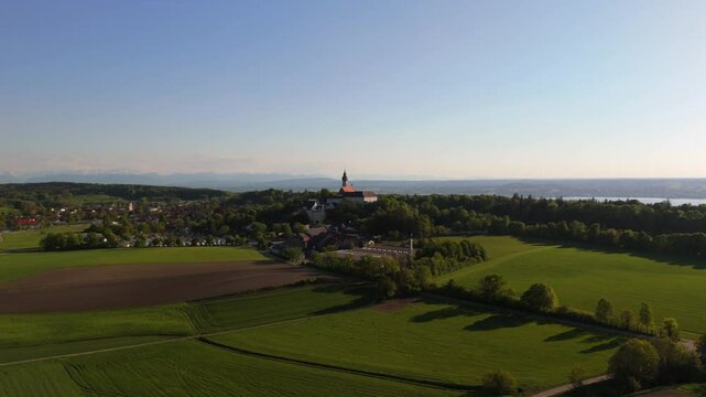 Aerial drone video of Kloster Andechs and pilgrimage church on Holy Mountain by Lake Ammersee, Bavaria, Germany. Scenic sunset view of monastery, nature, and rural landscape near Munich