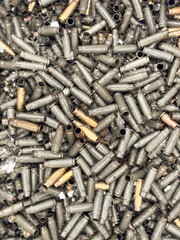 Wet, snowy, empty cartridge cases for a machinegun, carbine or rifle. Background of shiny cartridges to illustrate armed conflict, war or shooting events. Military background.