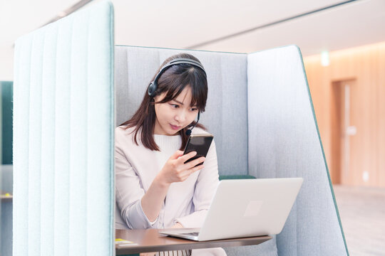 リモート会議をサボってスマホを使う若いビジネスパーソン
