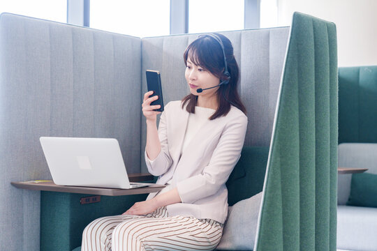 リモート会議をサボってスマホを使う若いビジネスパーソン