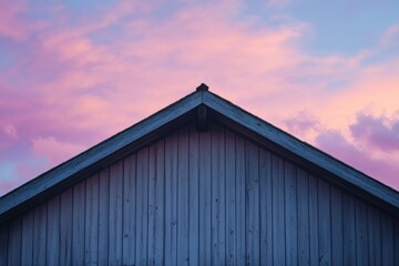 A low-angle view of a peaked roof against a vibrant sunset sky.