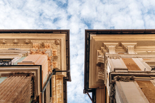 Genoa, Italy - September 22, 2024: Ornate cornices and stucco details of historic palazzi face each other above a narrow street in the UNESCO-listed city center.