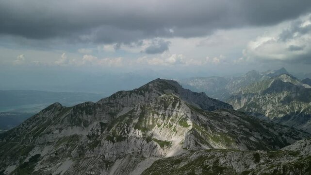 Aerial view from a drone flying over rocky mountains under a cloudy sky in summer in Levico Terme