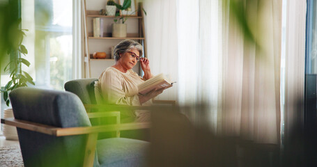 Senior, woman and reading a book on sofa for knowledge, learning information or retirement hobby. Elderly person, relax and fiction novel in living room for literature, weekend break or story in home
