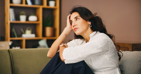 Thinking, sad and woman in home on sofa with anxiety for issue, depression and reflection in living...