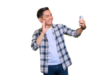 Cheerful young Asian man in plaid shirt doing selfie shot on mobile phone waving hand isolated on transparent background