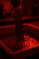 Moody analog film strip developing under red darkroom light