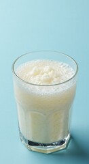 Creamy White Smoothie in a Glass on Aqua Background