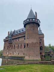 Exterior view of the majestic De Haar Kastel in the Netherlands, showcasing its impressive towers, moats, and red-brick architecture