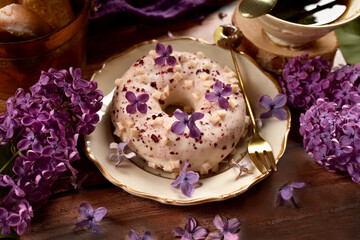 Delicious donut with white chocolate glaze and black berry filling with purple lilac decoration