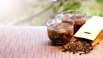 Two glass cups of herbal green tea and a pack of dry tea.