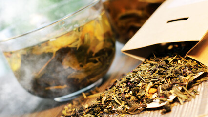 Two glass cups of herbal green tea and a pack of dry tea.