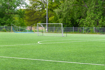 Empty soccer field with goal on green artificial grass with trees