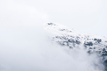 Snow-covered mountain slope emerging from fog