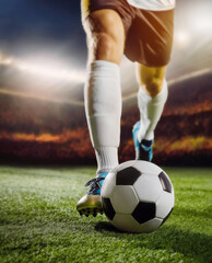 Closeup soccer player legs dribbling the ball on the pitch. Running man footballer at stadium on a field with full tribunes in the background