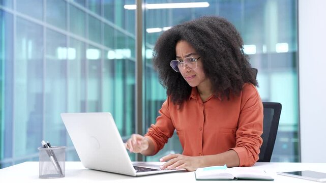 Frustrated african american businesswoman complains about poor performance of software on laptop sitting in business office. Angry black woman is dissatisfied with work of computer, internet, service