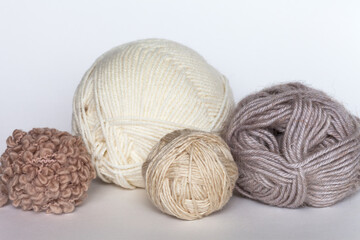 Different types of wool yarn for hand knitting in beige colors on white table. Merino wool, wool-acrylic blend, boucle yarn in balls and skeins. Knitting as hobby. DIY concept. Close-up. Front view