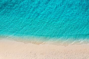 Beautiful bright sea with waves splashing on beach sandy shore. Summer seascape beautiful waves blue sea water in sunny day. Top view from drone. Scenic aerial view amazing tropical nature background