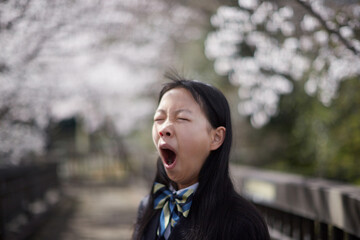 春の桜満開の公園で疲れた女子中学生の姿