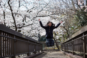 春の桜満開の公園で遊ぶ元気な女子中学生の姿