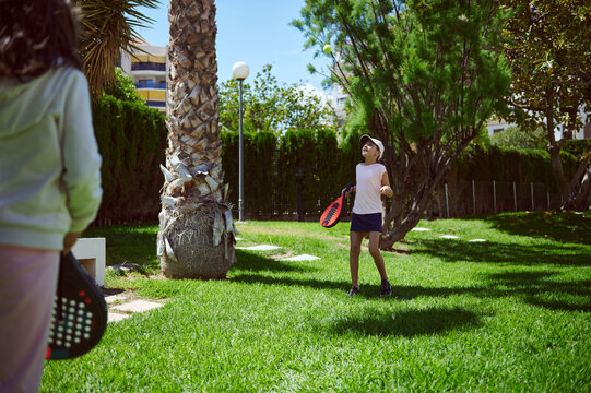 Children Enjoying Paddle Tennis In A Sunny Park Setting
