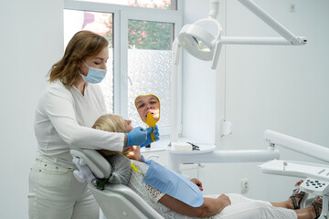 Fototapeta premium Senior female patient with dentist looks in the mirror and having dental treatment at dentist's office
