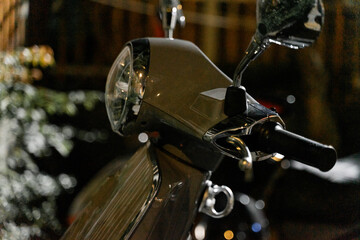 a classic scooter parked under the city lights at night. The gleaming chrome details and the iconic...