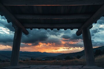Rustic wooden shelter frames sunset over mountain valley.