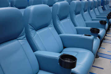 rows of comfortable powder-blue leather seats with built-in cup holders in a modern theater