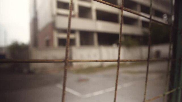 Close-up of a fence mesh against the background of slums, a building under construction.