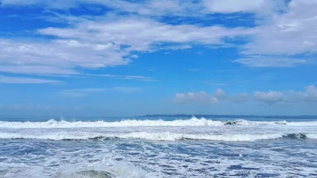 Landscape of crashing wave with sky cloud background.In the blue sea the wave rolling and soar.Breaky wave into foam then flow toward beach and meet with back current,creating a small crash and splash