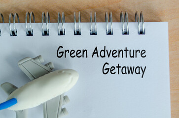 Green Adventure Getaway text on white notepad. Green travel planning and environmental awareness