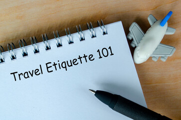 Travel Etiquette 101 text on white notepad with airplane and black pen background