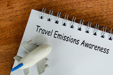 Travel Emissions Awareness text on white notepad with small airplane background. Environmental...