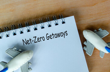 Top view of Net Zero Getaways text on white notepad with small airplanes background. Environmental...