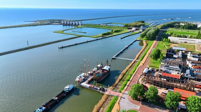 High angle view at the reconstruction of the VOC ship Batavia at Museum Batavialand. Splendid scenery of the waterscape with dikes and sluice. Lelystad, the Netherlands.