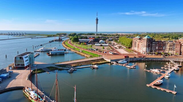 Marina with several berths and boats near them. Approaching the tower for television broadcasting in the scenery of Lelystad, the Netherlands.