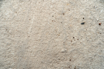 Textured concrete surface with small stones and imperfections.