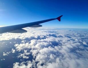 Fototapeta premium Airplane wing above fluffy clouds and blue sky. Perfect for travel, adventure, freedom concepts.