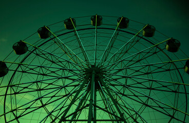 Ferris wheel shining green at dusk in amusement park