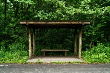 A covered rest area with a bench sits amid a forest. Lush greenery behind the structure