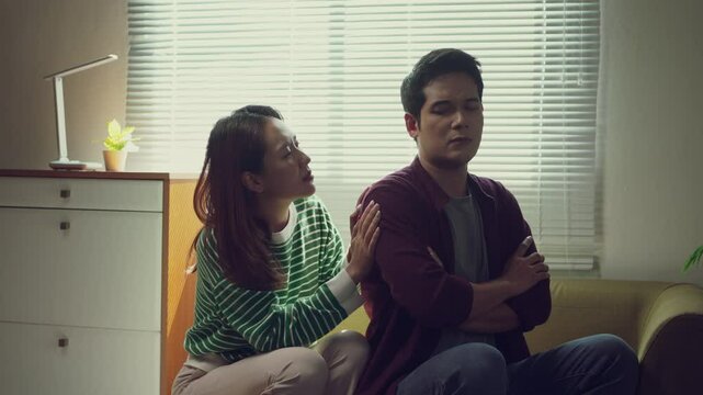 Young woman showing deep emotional support, gently comforting her boyfriend experiencing sadness while sitting together on living room sofa, demonstrating relationship empathy and understanding