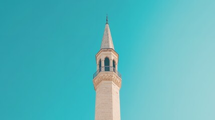 A minaret stands tall against a clear blue sky with its ornate details and pointed spire reaching upward