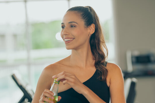 Young hispanic with energy drink woman workout at gym