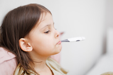 child is sick in bed. little girl measures body temperature. Concept disease, pharmaceutics.
